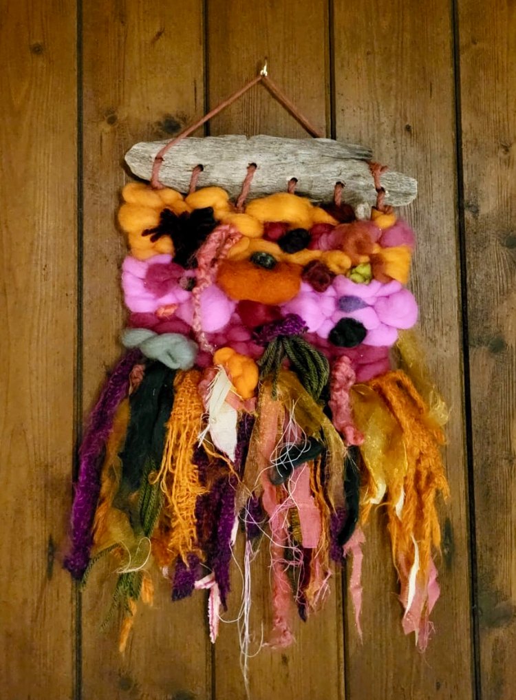 Colorful woven wall hanging on a wooden panel background